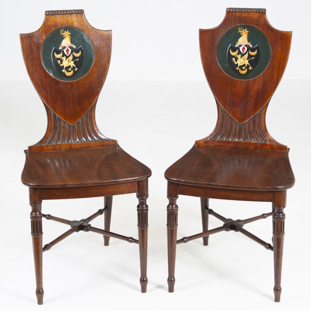 A matching  pair of 19th century mahogany shield back hall chairs bearing the arms of D'Aeth of Knowlton Court, Kent,  made for Sir Narborough D'Aeth, 3rd baronet of Knowlton.